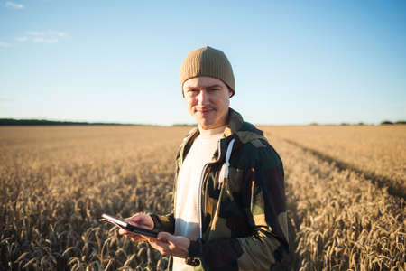 man farmer with tablet in field of wheat. Smart farming and digital agricultureの写真素材