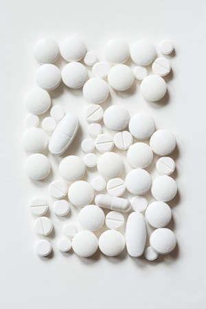 tablets of various shapes on white background close up top view. minimalistic concept of medicine and treatment. rectangle shape.の写真素材