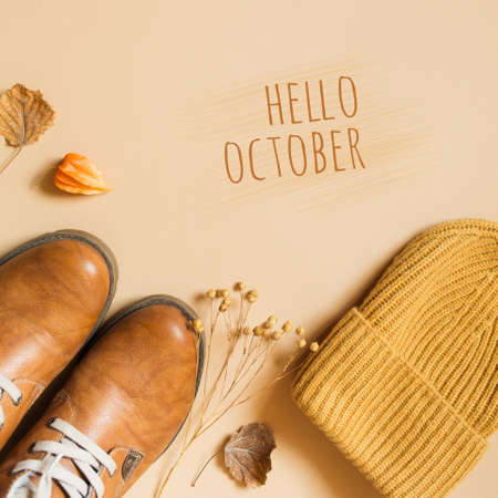 yellow knitted beanie hat, orange shoes and dry autumn leaves on a beige background. concept of...