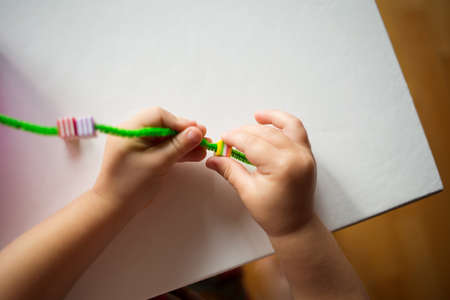 child stringing beads on string. development of baby's fine motor skills. learning in kindergarten.の写真素材