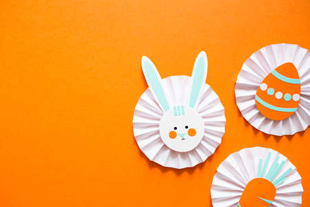 easter paper craft for kids. paper DIY egg, bunny and carrot on orange background. create art for children. copy space.の写真素材