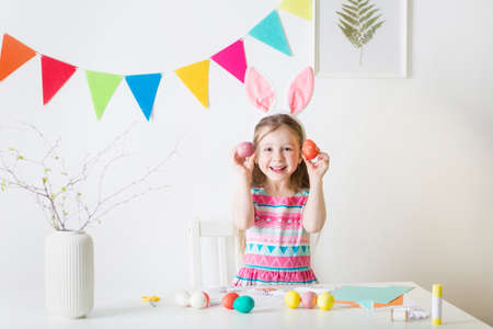 happy girl with bunny ears and easter eggs in her hands. materials for art craft creativity on...