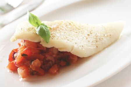 Halibut With Tomatoes Served On A White Plateの写真素材