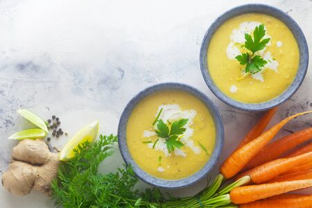 Two Bowls Of Carrot Soup With Ingredientsの写真素材