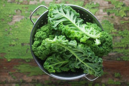 Raw Kale in A Sieve On A Green Wooden Background