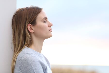 Side view portrait of a serious melancholic woman looking away on the beachの写真素材