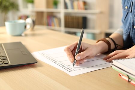 Close up of student girl hand writing schedule on weekly planner on a desk at homeの写真素材