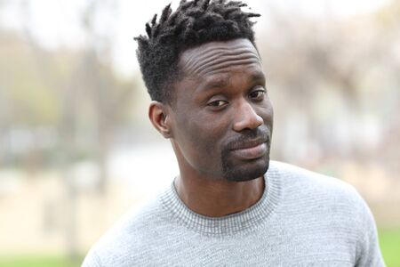 Suspicious black man looking camera standing outdoors in a parkの写真素材