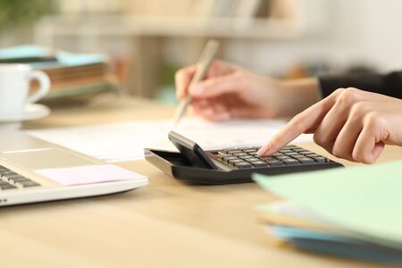 Close up of entrepreneur woman hands calculating with calculator on a desk at home