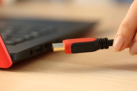 Close up of woman hands plugging hdmi cable on laptop on a deskの写真素材