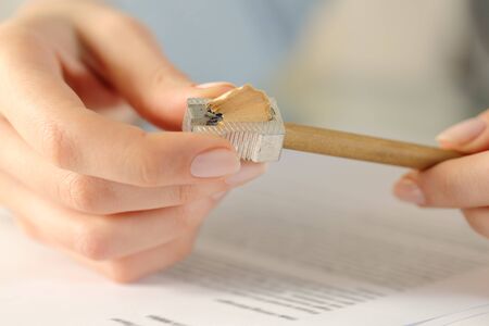 Close up of woman hands sharpening pencil on a desk at home or officeの写真素材