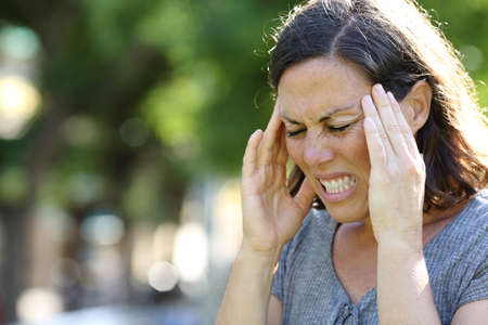 Adult woman in pain suffering sore throat sitting in the sofa at home