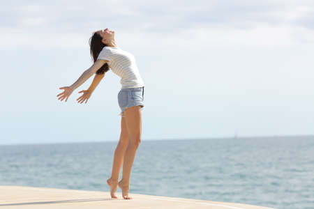 Full body profile of an excited woman with long legs breathing fresh air on the beach