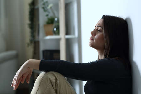 Side view portrait of a sad depressed woman complaining alone at home in the night