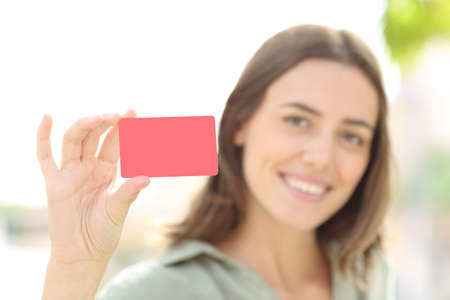 Happy woman showing blank credit card outside in the street
