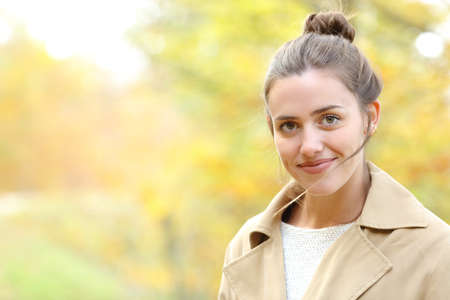 Portrait of a happy woman looking at camera in a park in autumn