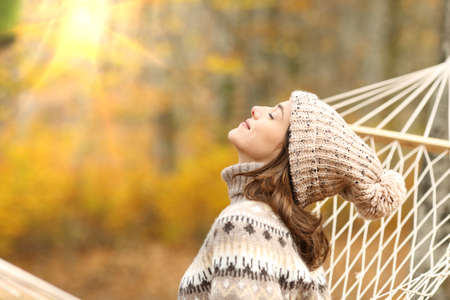 Side view portrait of a relaxed woman breathing fresh air sitting on a rope hammock in autumn in a forestの写真素材