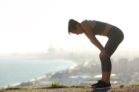 Side view portrait of an exhausted runner resting after sport in city outskirts