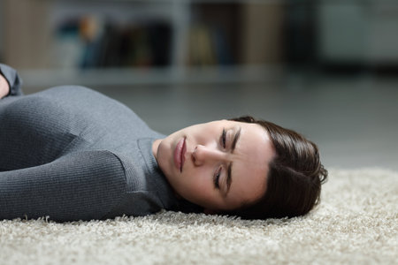 Sad woman looking away lying on a carpet on the home floorの写真素材