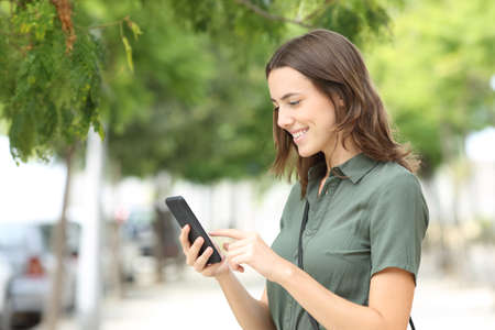 Happy woman walking using smart phone in a city streetの写真素材
