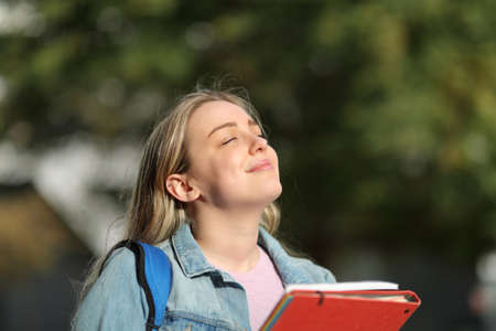Happy student breathing fresh air standing in a park or university campusの写真素材