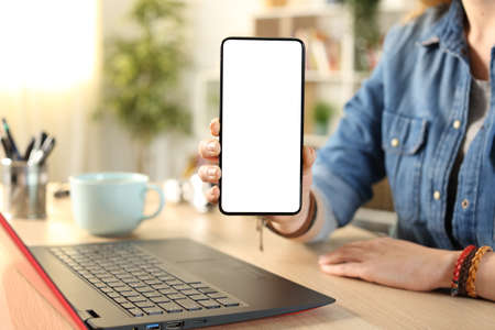 Close up portrait of a student hand showing blank smart phone screen on a desk at homeの写真素材