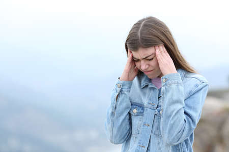 Stressed woman suffering migraine in the mountain