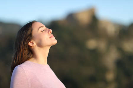 Relaxed lady breathing fresh air in the mountainwith a warm light