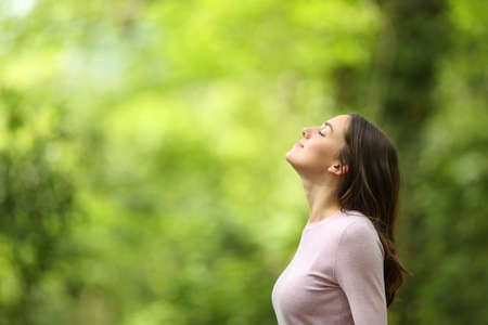 Profile of a relaxed woman breathing fresh air in a green forestの写真素材