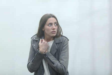 Scared casual woman walking alone looking at side in a foggy park