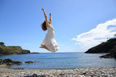 Profile of a happy woman in white jumping on the beach celebrating vacation a sunny day