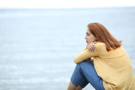 Serious pensive woman contemplating on the beach