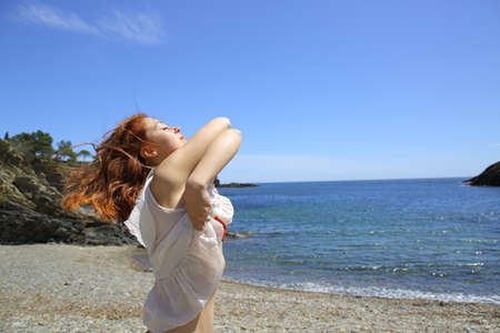 Profile of a woman undressing on the beach ready to bath a sunny day