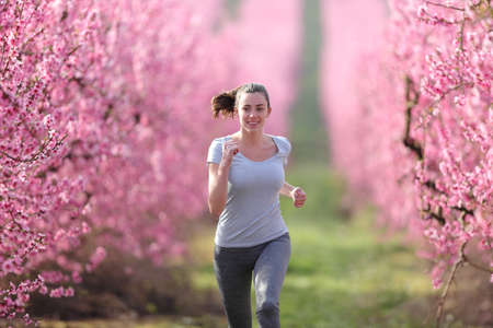 Front view portrait of a runner running in a pink field in springtimeの写真素材