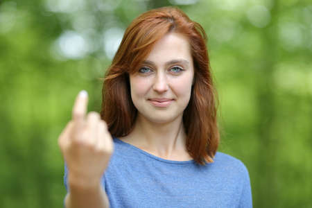 Front view portrait of a redhead woman saying come here beckoning in a forest or parkの写真素材