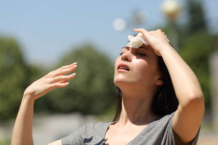 Stressed asian woman drying sweat with a cloth in a warm summer dayの写真素材