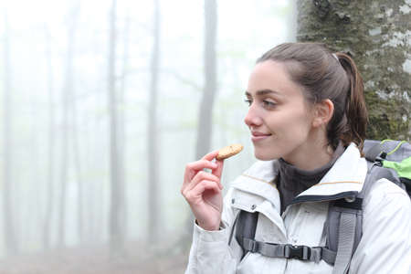 Satisfied trekker resting eating cookie in a forest