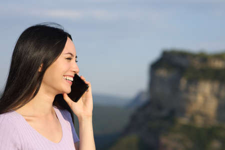 Asian woman talking on mobile phone smiling in the mountainの写真素材