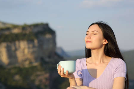 Asian woman drinking coffee relaxing at sunset enjoying nature