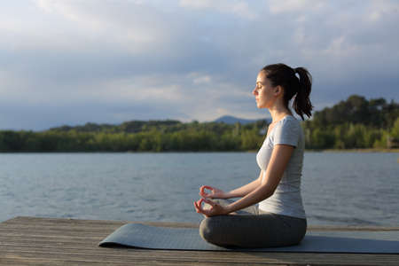 Profile of a relaxed woman doing yoga exercise in a lake at sunset