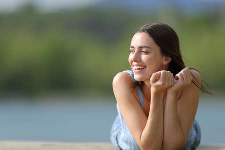 Front view portrait of a happy woman lying on pier looking at sideの写真素材