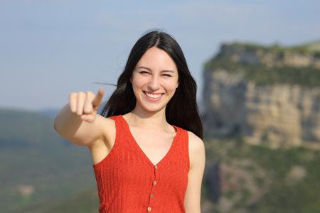 Front view portrait of an asian woman pointing at camera in the mountainの写真素材