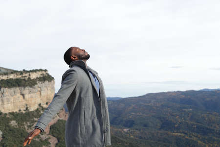Relaxed man with black skin breathing fresh air wearing jacket in winter in natureの写真素材