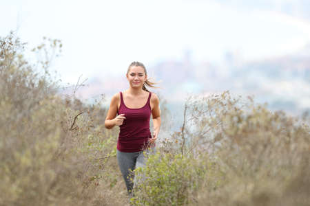 Front view portrait of a happy teen running in the mountain alone