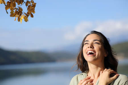 Happy beauty woman laughing outdoors in nature looking above