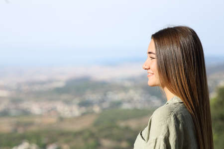 Side view porrtait of a happy teen contemplating views standing outdoorsの写真素材