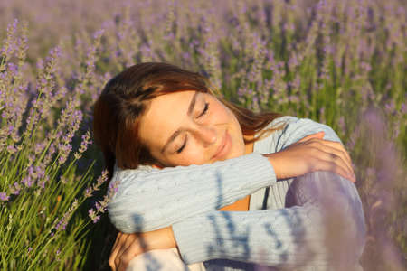 Happy woman relaxing with closed eyes sitting in lavender fieldの写真素材