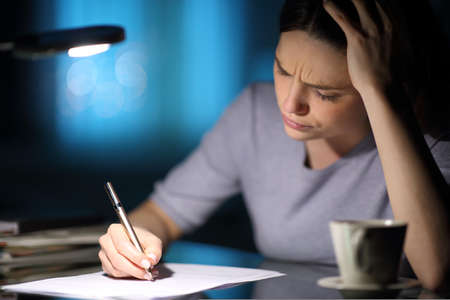 Worried woman is reading to filling form in the night at home