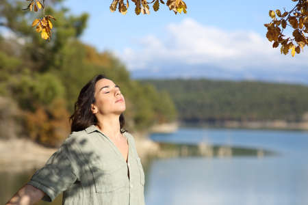Woman breathing fresh air relaxing in a lake in autumn