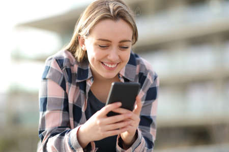 Happy teen checking smartphone content in the street